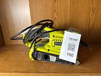 Ryobi corded belt sander front and side view with tag number 166 showing power cord wrapped around the tool.