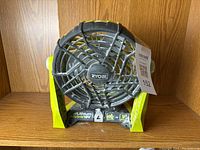 Front view of Ryobi One+ 18V cordless portable fan showing brand logo, internal grill, and battery slot