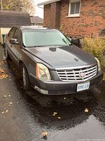 Front passenger-side view of gray sedan parked in driveway, showing front grille, headlights and body panels