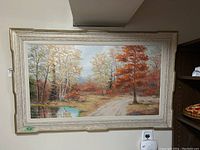 Front view of framed fall woodland painting showing path, pond and trees