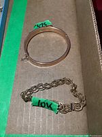Overview showing a hinged bangle stamped .375 and a rope chain link bracelet stamped 10kt in cardboard box