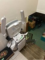 Overview of stair lift mounted on stair rail showing seat, armrests, footrest and track