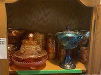 Shelf view showing footed lidded candy dish with lid, compotes and tumblers behind