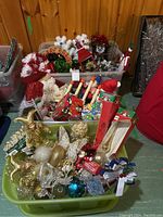Two plastic totes—green tote of gold and multicolor ornaments; clear tote of red and white decorations and garland