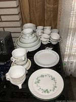 Four Ivy Wreath dinner plates with twisted rim and matching mugs behind