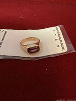 Front view of ring showing rectangular purple gemstone bezel set in yellow gold