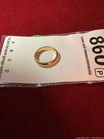 Yellow gold band ring resting on auction lot tag