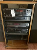 JVC stereo components including amplifier, tuner, CD changer and cassette deck stacked in a wooden shelving unit.