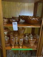 Two wooden shelves filled with small bowls, tall water glasses, sugar and cream pieces