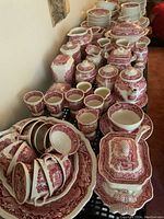 Angled view of assembled set on table showing lined up pitchers, covered dish, cups, bowls and plates