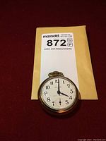 Front view showing the white dial, black Arabic numerals, black hands, subsidiary seconds dial, and the crown at the top.