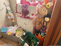 Wide view of multiple seasonal decorations set in corner including Valentines towels, Fall scarecrows, and witches