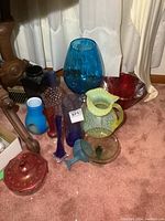 Wide view of all glass items on carpet including vases, pitchers, and bowls