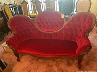 Front view of red velvet tufted parlor sofa with carved wood frame