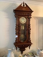 Full front view of wooden pendulum wall clock with weights