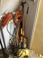 Photo showing Signal electric pressure washer, orange extension cords, and yard tools leaning against a wall.