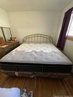 Full view of assembled king size brass bed frame with mattress and boxsprings