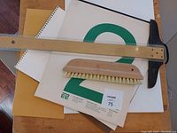 Top view of the entire lot including clipboards, paper pads with visible branding, drafting T-square and brush arranged on the floor.