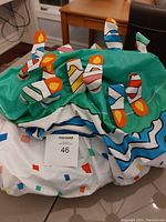 Photo of folded colorful inflatable birthday cake with candle designs on top, showing fabric with blue, green, white, and multicolor accents.