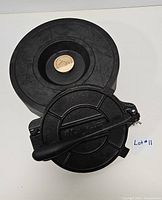 Cast iron tortilla press with handle, placed on top of the cast iron tortilla warmer, showing overall condition and design