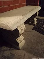 Concrete bench close-up showing carved ornamental edge detail along the rectangular seat.