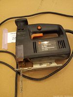 Full view of the Black & Decker jigsaw showing the body, handle, cord, metal base plate and attached saw blade.