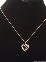 Sterling silver necklace with heart-shaped pendant displayed on black background, showing full necklace length and pendant design.