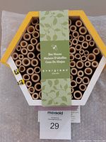Front view of hexagonal bee house nest showing round hollow tubes and product label.