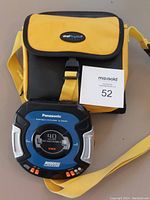 Panasonic portable CD player with attached yellow and black carrying case and a numbered lot card
