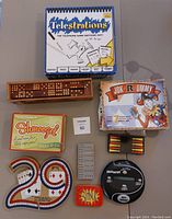 Photo shows a variety of board and card games including Telestrations, Cribbage boards, Shmoozel, Blink, Jok-R-ummy, and an electronic game.