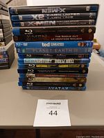 Stack of Blu-ray and DVD movies showing X-Men series and various other titles.