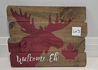 Front view of wooden welcome sign with moose graphic, maple leaf, and text