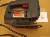 Black Skil jig saw with power cord and orange trigger, indicating used condition with minor wear.