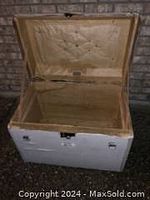 Open view of antique leather trunk showing beige quilted padded interior lining