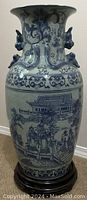 Full view of the large blue and white Asian porcelain vase on wooden stand