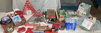 Wide photo showing array of Christmas cards, gift wrap, tins, advent calendars, and party supplies including napkins and cups, arranged on a surface.