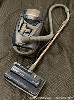 Kenmore canister vacuum with hose, metal wand, and power head attachment on dark background.