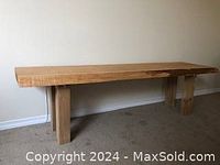 Full view of the live edge cedar wood table against a wall, showing natural wood edges and block legs