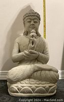 Large stone Thai Buddha statue seated in lotus position holding object
