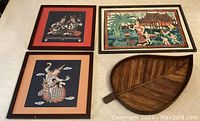 Overview photo showing three framed prints and leaf-shaped wooden platter on light carpet background