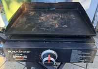 Top front angle photo of Blackstone Adventure Ready grill showing flat top griddle with rust and residue, single control knob, and brand markings.