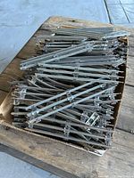 Top view of a box filled with numerous vintage Lionel metal model train track sections, mostly straight pieces visible.