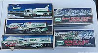 Top view of 5 boxed Hess vehicles arranged on a table, showing box artwork and condition.