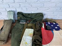 Top-down view of the military lot items laid out on a brick surface. Shows two flags, map, bags, and other items.
