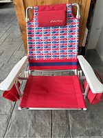 Front view of Nautica beach chair showing the red fabric seat, patterned back with fish design, and Nautica logo flap.
