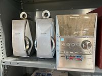 Two Panasonic silver speakers positioned side-by-side showing design and size relative to the main stereo unit.