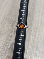 Front view of the sterling silver ring with amber stone on a sizing stick showing size 8.