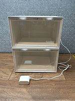 Two SupBro shoe boxes stacked, showing transparent doors and power adapter in front