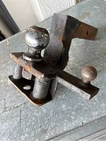 Trailer hitch and ball mount assembly showing top and side view, with rust and wear visible on metal parts.