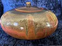 Side view of the ceramic fire pot showing its rounded shape and earthy glaze with reddish and brown tones.